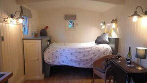 Et hyggeligt soveværelse med seng, sengebord, lampe og et lille skrivebord med stol.