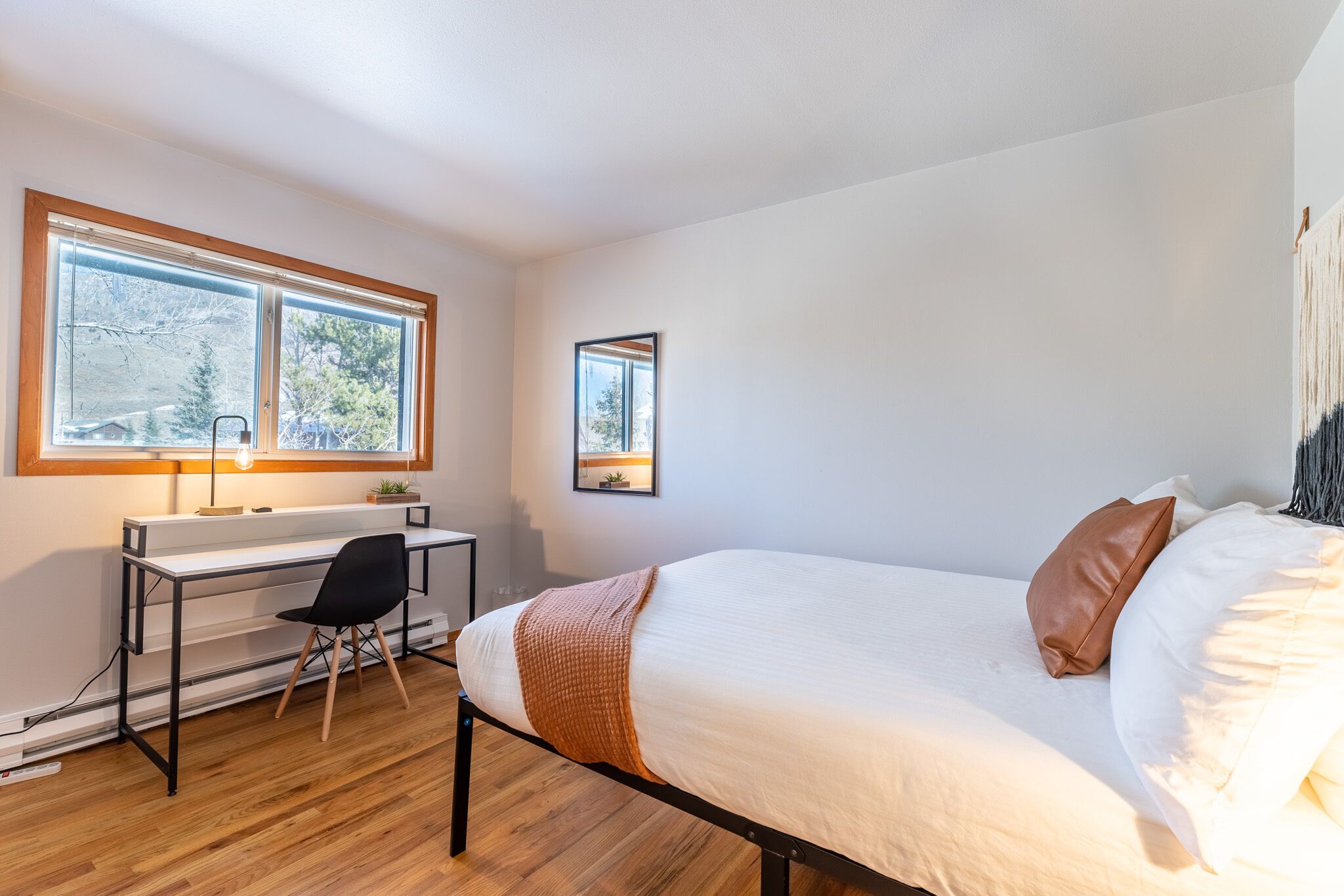 A bedroom with a bed, a desk, a chair, and a window.