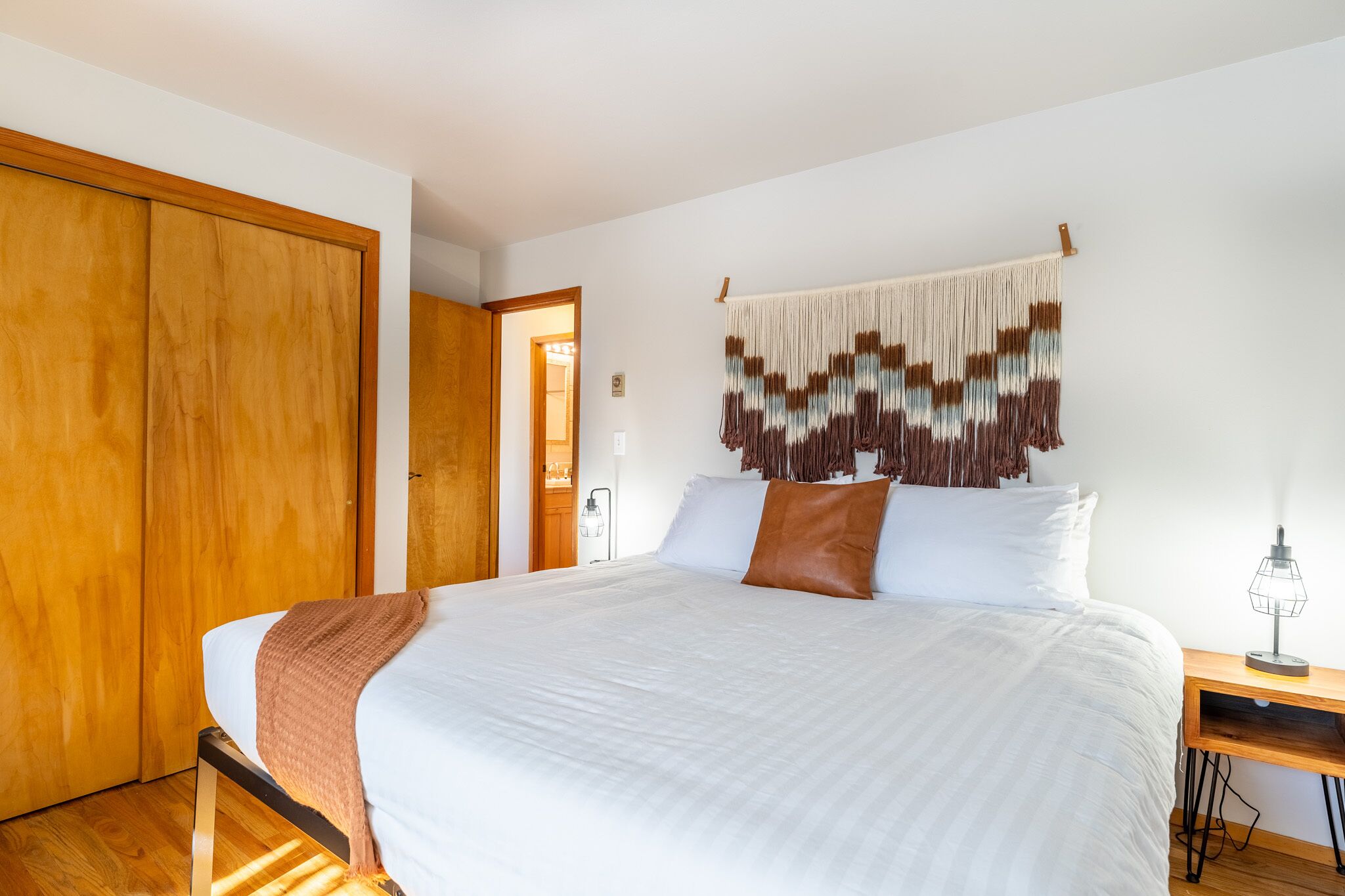 Een slaapkamer met een groot bed, een houten garderobe en een wanddecoratie.