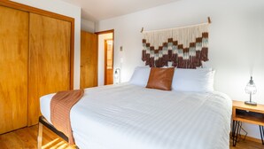 Een slaapkamer met een groot bed, een houten garderobe en een wanddecoratie.