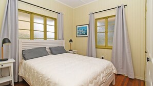 Un dormitorio con cama, mesitas de noche, lámpara y cortinas.