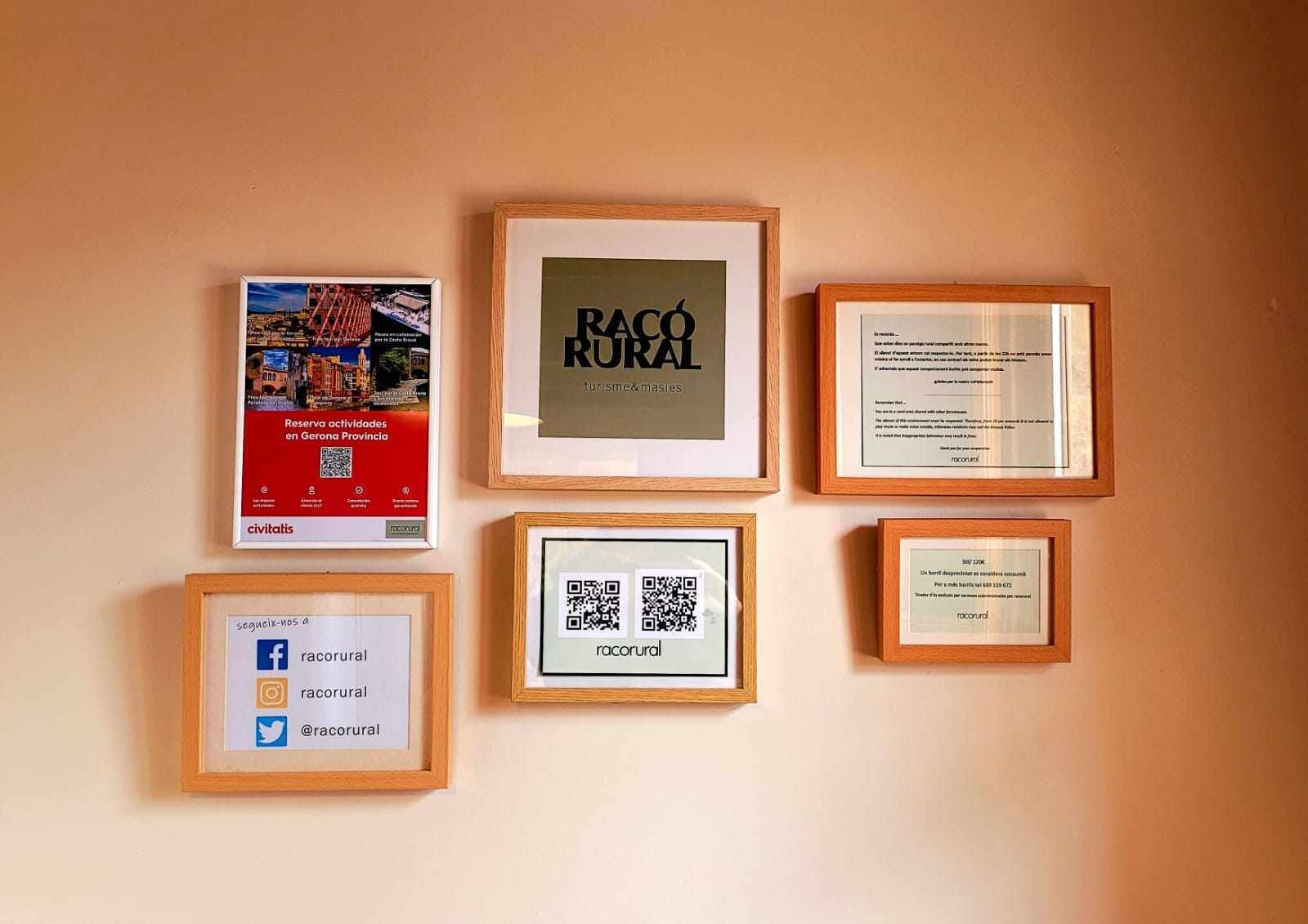 A wall with six framed items, including a QR code, social media handles, and text.