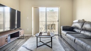 Un salon équipé d’un téléviseur à écran plat, d’un canapé en cuir, d’une table basse et d’un balcon avec vue.