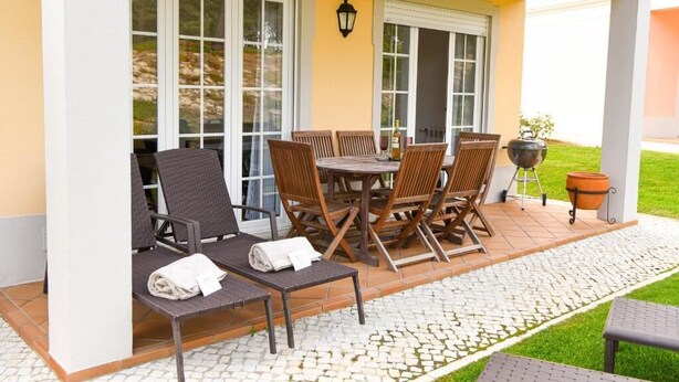 An outdoor patio with a table and chairs, a grill, and a potted plant. - Burgo D. Sebastião 27B (Óbidos)