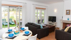A living room with a dining table, sofas, a TV, and a fireplace. - Burgo D. Sebastião 27B (Óbidos)