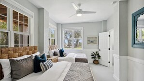 A bedroom with two beds, a ceiling fan, and large windows. - Large Peaceful Home | Hot Tub, Dock Near Beach (Savannah)