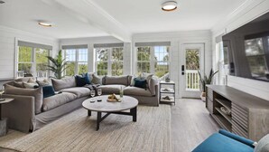 A spacious living room with a large sectional sofa, a round coffee table, and a flat-screen TV. - Large Peaceful Home | Hot Tub, Dock Near Beach (Savannah)
