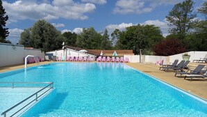Una piscina con agua cristalina y azul, rodeada de sillones de playa y sombrillas.