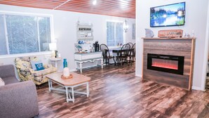 A living room with a fireplace, a television, and a dining area with chairs and a table. - Dreamy River Cottage (Inverness)