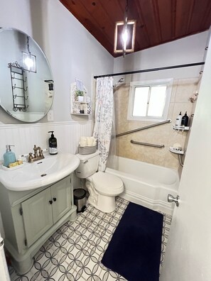 A bathroom with a white sink, toilet, and bathtub. There is a mirror, a shower curtain, and a window. - Dreamy River Cottage (Inverness)