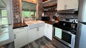 A kitchen with white cabinets, a brick backsplash, and stainless steel appliances. - Dreamy River Cottage (Inverness)