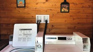 A room with a washing machine, a dryer, and a power strip on a wooden wall. - Quaint room overlooking the lake called   Hummingbird Haven - Curriers Lakeview (Rice Lake)