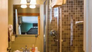 A bathroom with a glass-enclosed shower, a sink with a mirror above it, and a toilet. - Quaint room overlooking the lake called   Hummingbird Haven - Curriers Lakeview (Rice Lake)