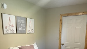 Una camera da letto con un letto, una porta e tre opere d'arte a parete.