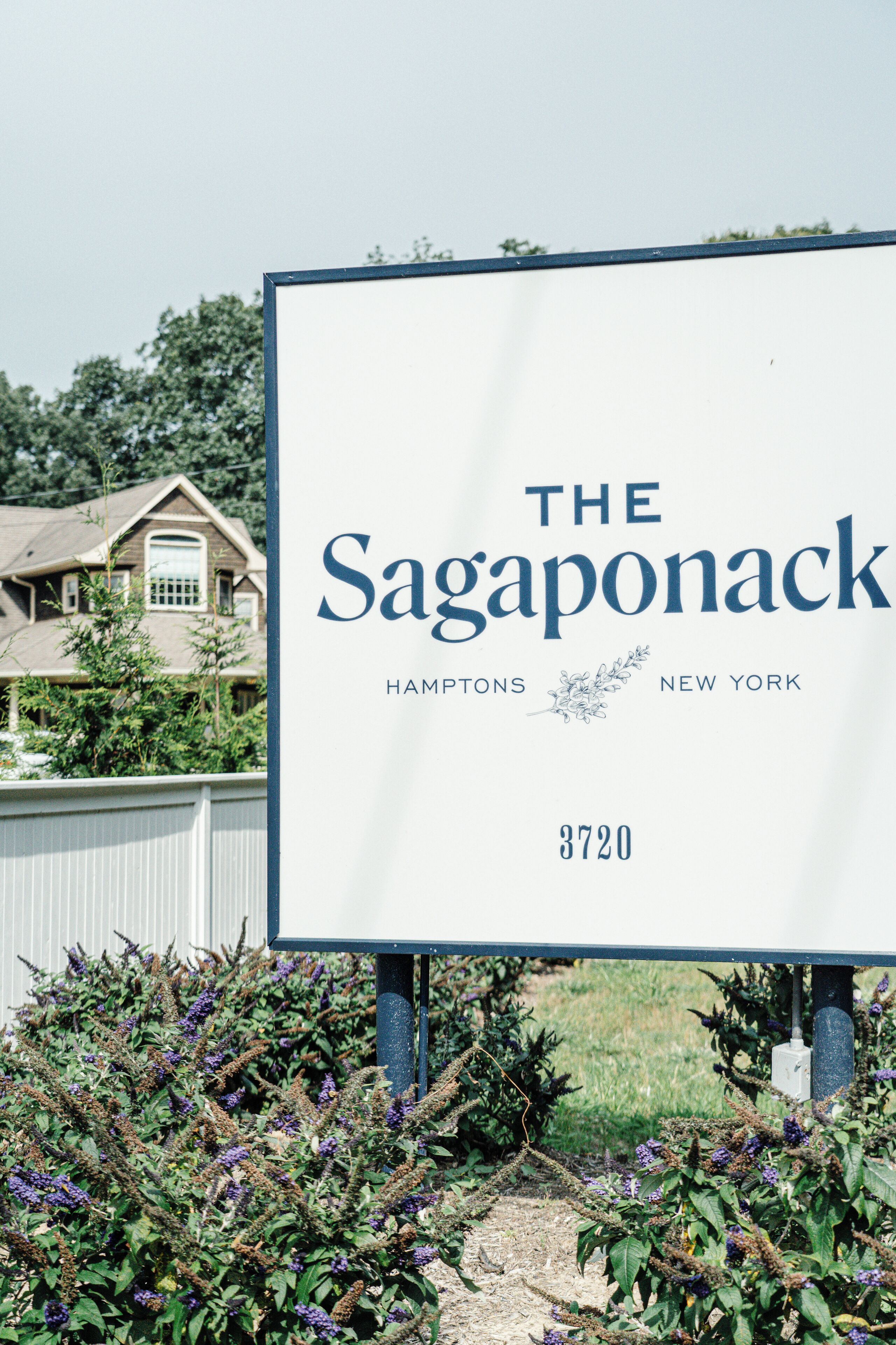 A sign for The Sagaponack in Hamptons, New York, with a house in the background.