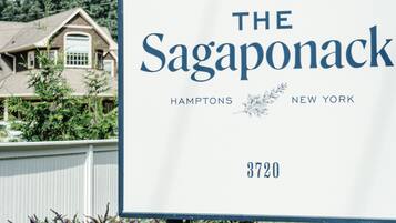 A sign for The Sagaponack in Hamptons, New York, with a house in the background.