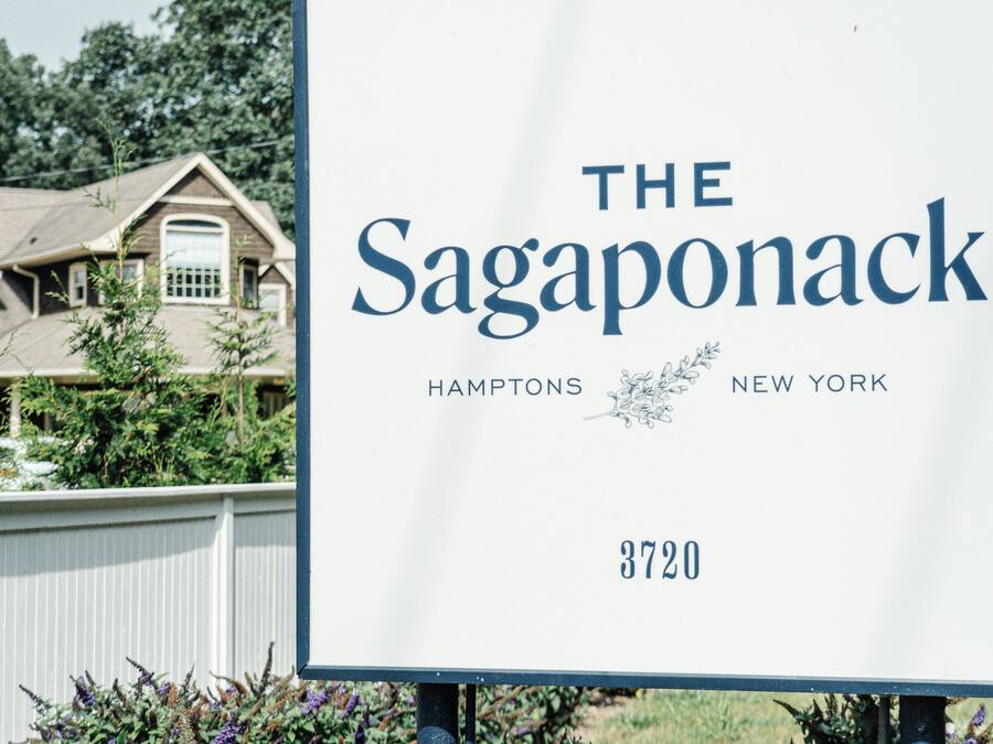 A sign for The Sagaponack in Hamptons, New York, with a house in the background.