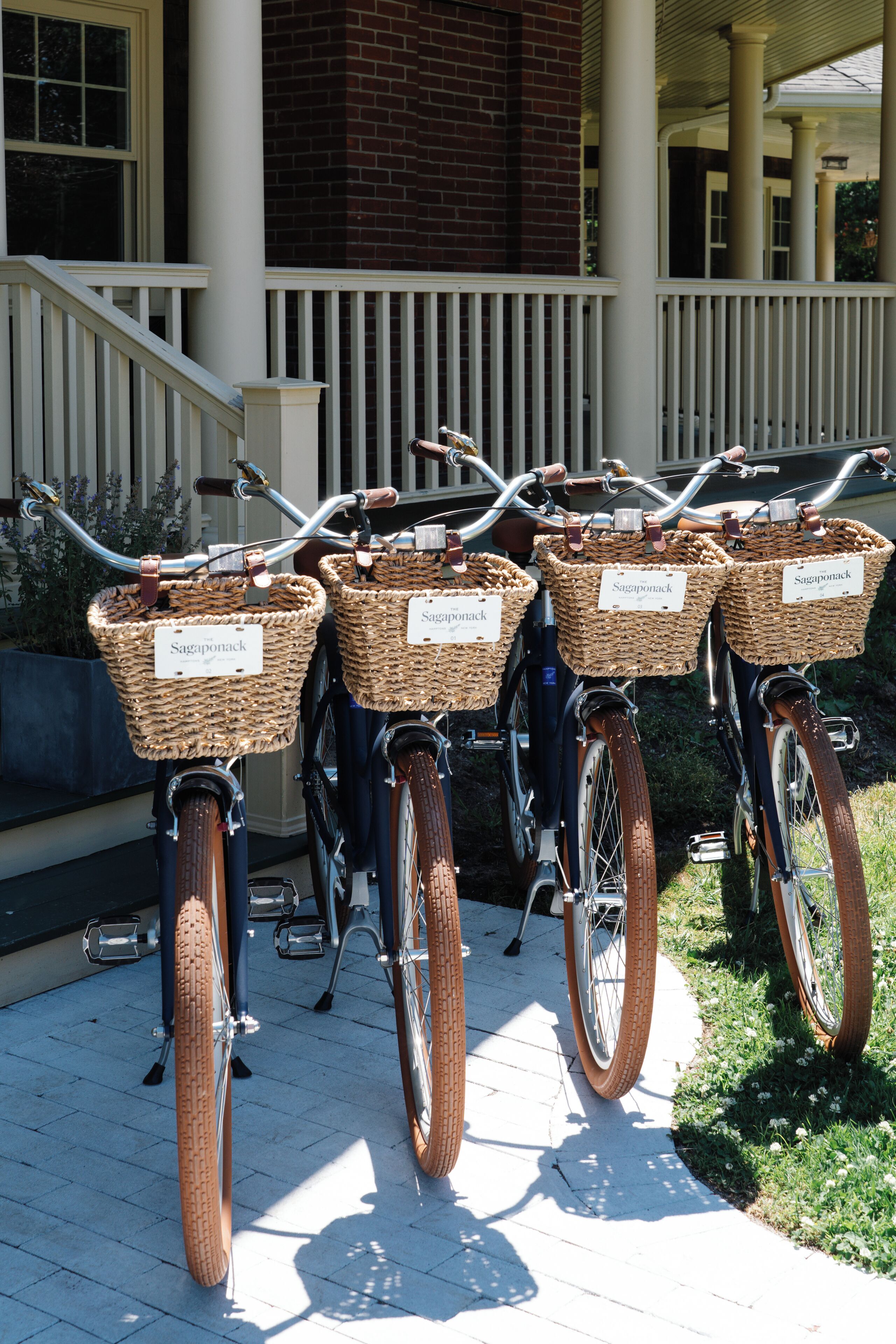 Tres bicicletas con cestas de mimbre etiquetadas 'Saginport' estacionadas sobre una terraza de madera.