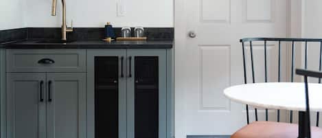Una cocina moderna con gabinetes grises, una encimera negra y una puerta blanca al fondo.