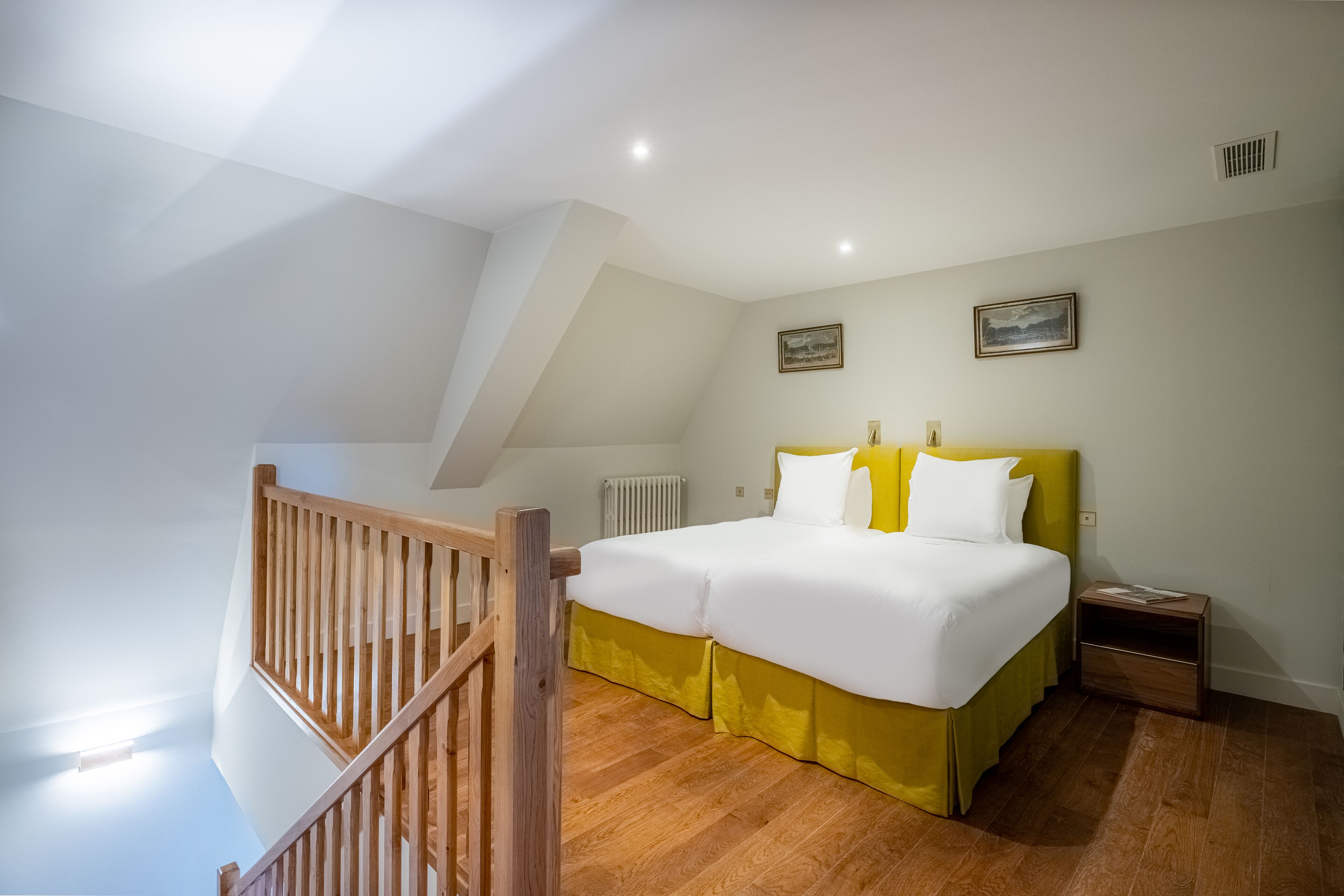 A bedroom with a bed, wooden floor, and a staircase.