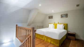 A bedroom with a bed, wooden floor, and a staircase.