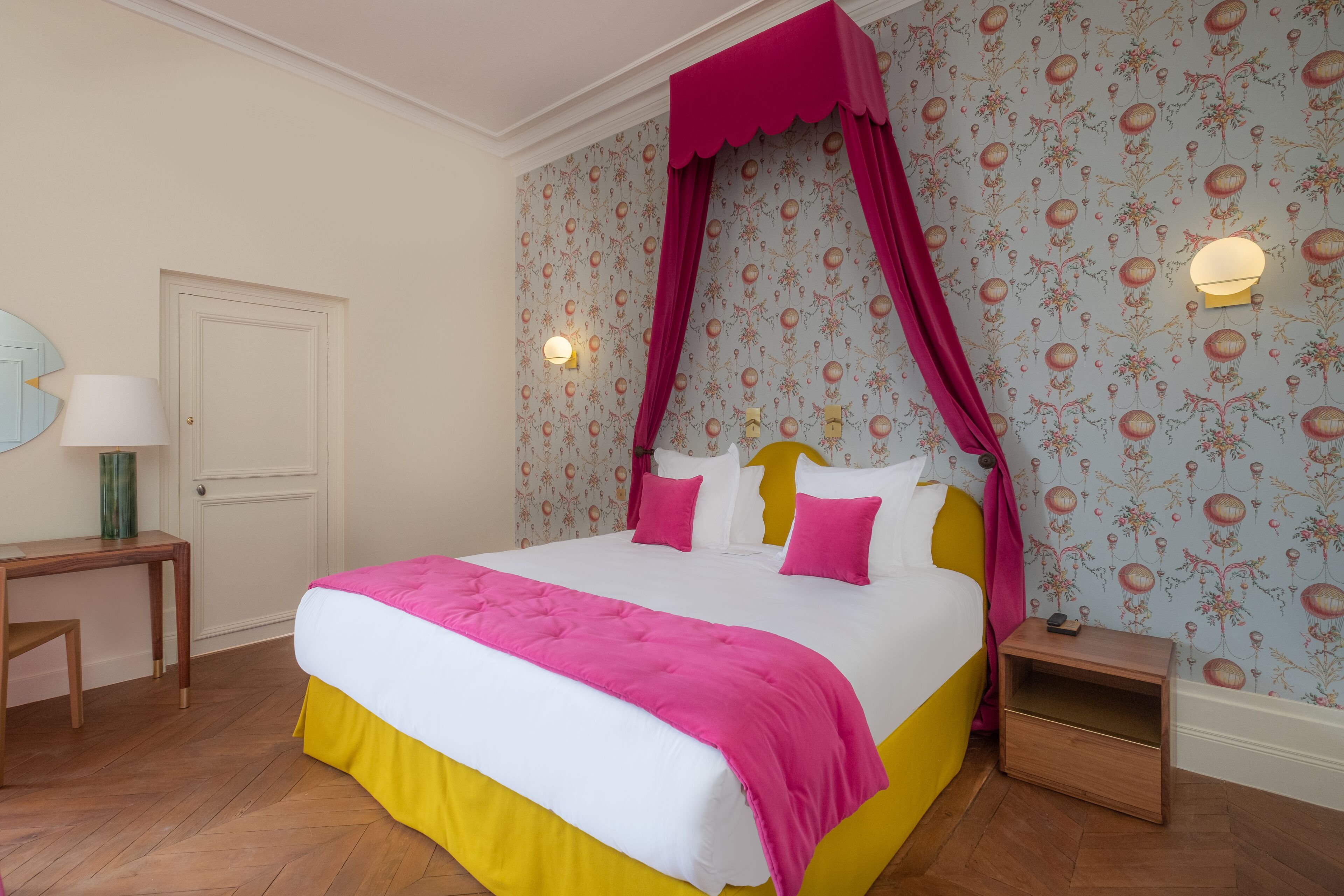 A bedroom with a bed, a nightstand, a lamp, and a door.