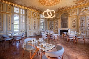 Uma sala de jantar imponente, com decoração de parede elaborada, janelas amplas e lareira.