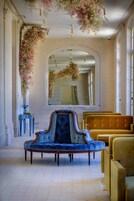 Um quarto com um espelho grande, um sofá azul e cadeiras amarelas.