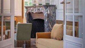 A room with a fireplace, a sofa, and a painting on the wall. - La Borde en Sologne Château & Spa (Vernou-en-Sologne)