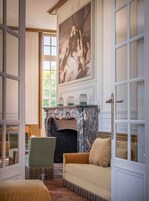 Um quarto com lareira, um sofá e um quadro na parede.