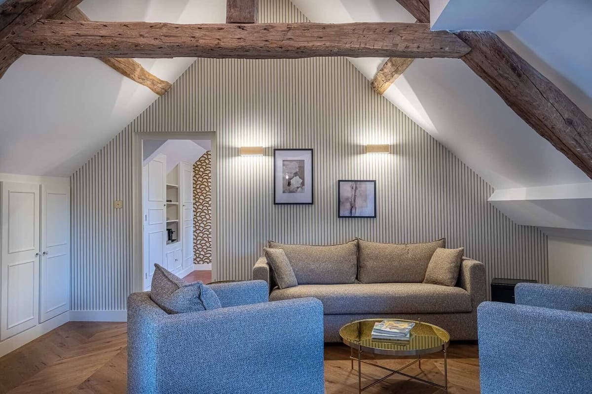 Een gezellige loft-living met een hoge plafond, zichtbare houten balken, en een gestreept muurontwerp.