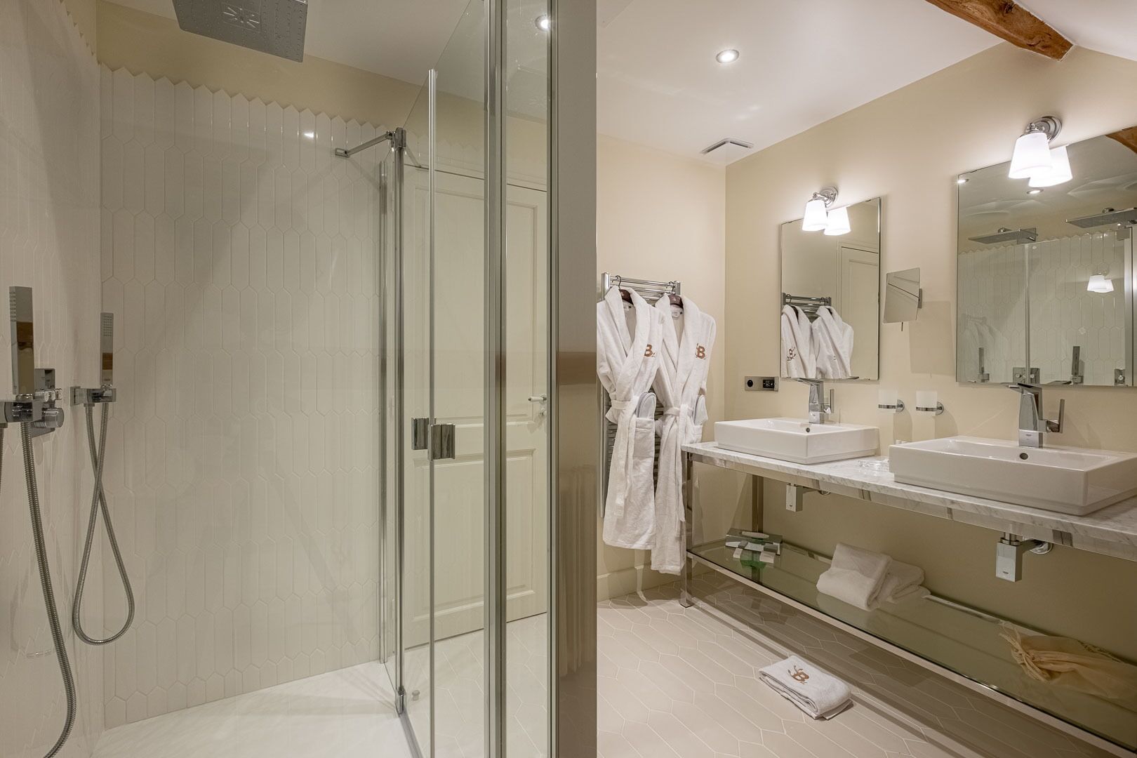 A modern bathroom with a glass-enclosed shower, two sinks, and a large mirror.