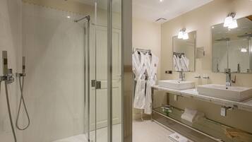 A modern bathroom with a glass-enclosed shower, two sinks, and a large mirror.