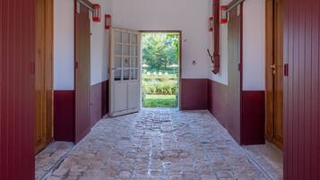 A corridor with red doors leading to a garden.