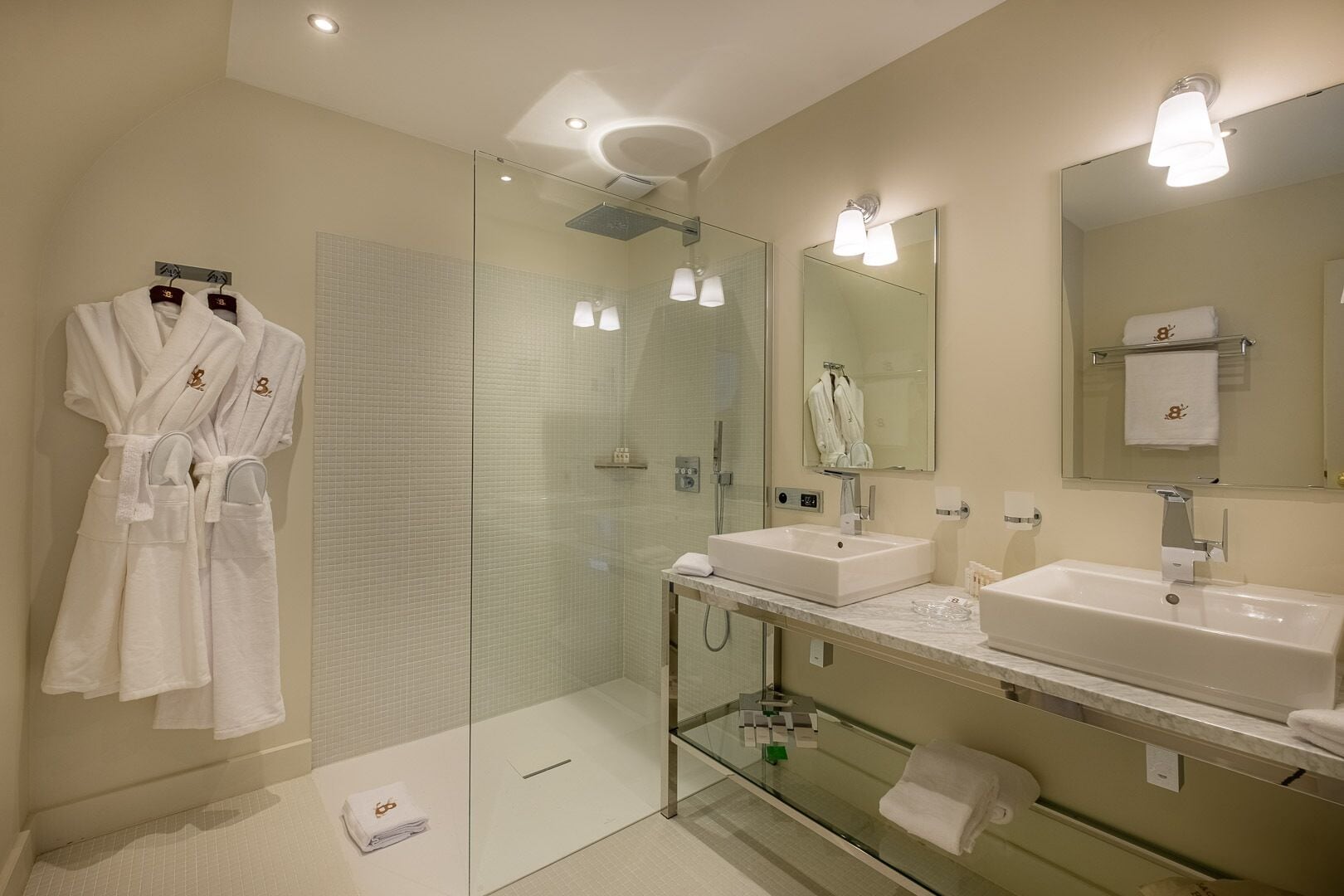 Un baño moderno con dos lavamanos, cabina de ducha de cristal y un espejo grande.