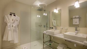Un baño moderno con dos lavamanos, cabina de ducha de cristal y un espejo grande.