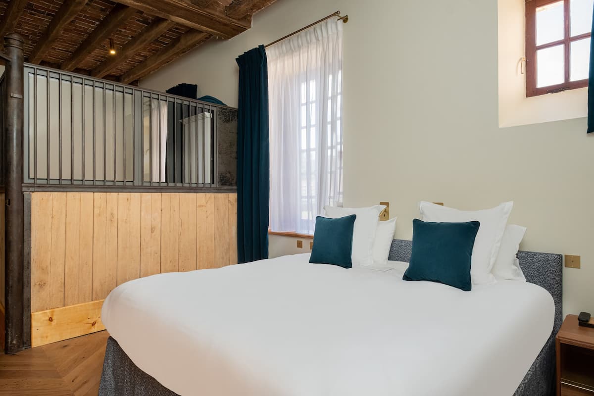 Een slaapkamer met een groot bed, houten wanden, een raam met gordijnen en een balkon.