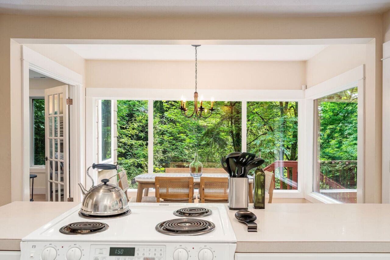 A kitchen with a white stove, a chandelier, and a dining table with chairs.