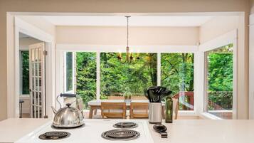 A kitchen with a white stove, a chandelier, and a dining table with chairs.