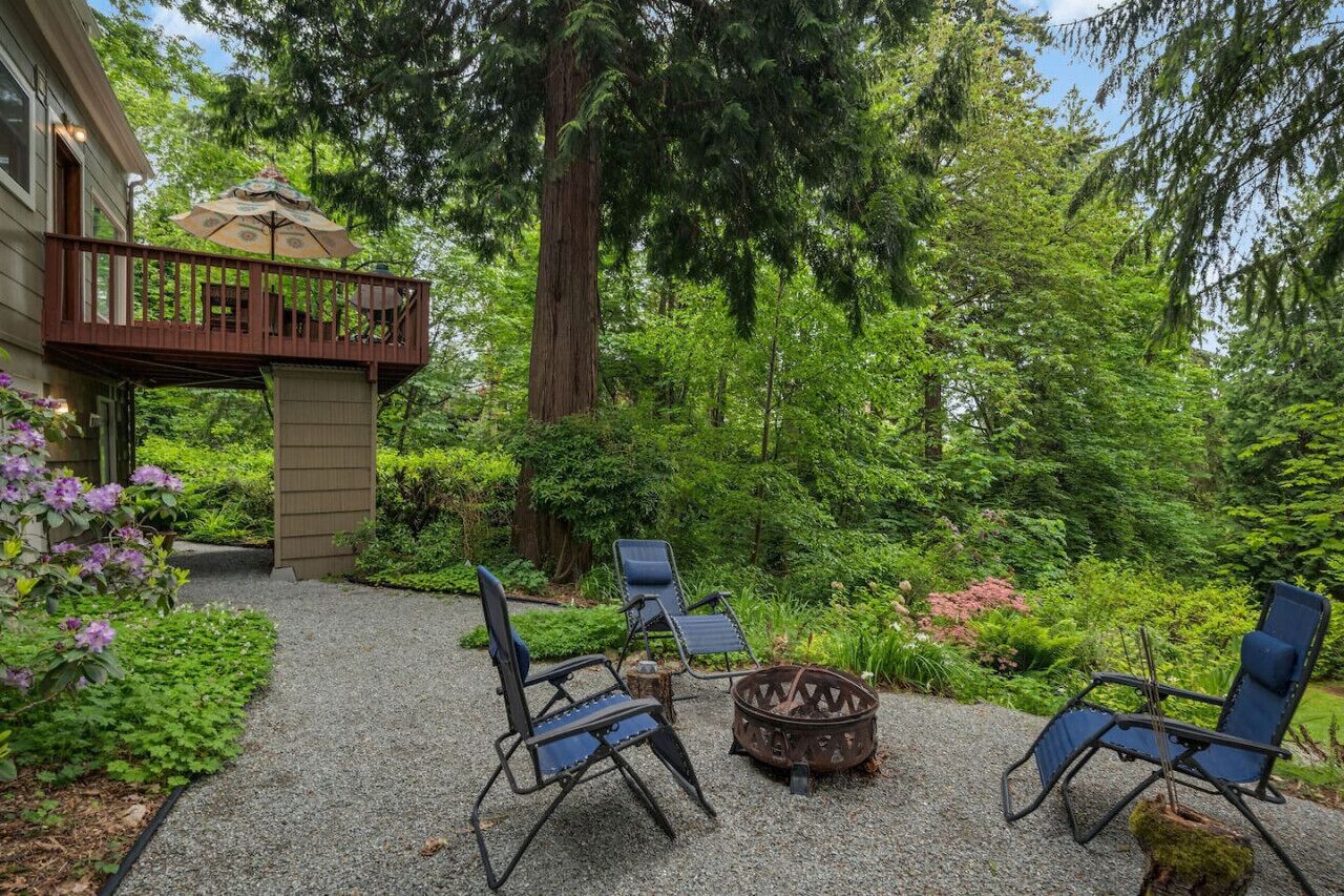 Une terrasse avec deux chaises longues, un foyer extérieur et une plateforme en bois dotée d’une rambarde.