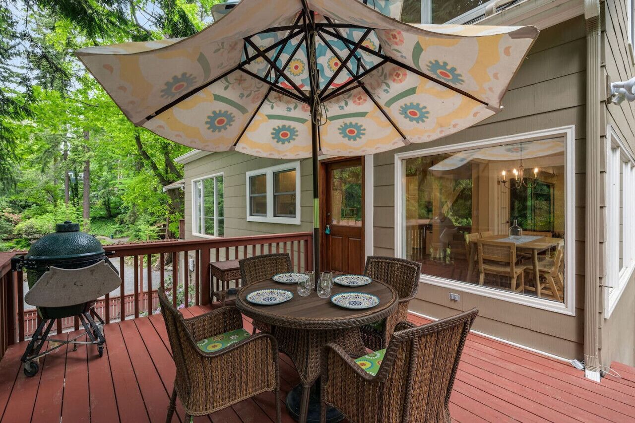 A deck with wicker furniture, a grill, and a large umbrella.