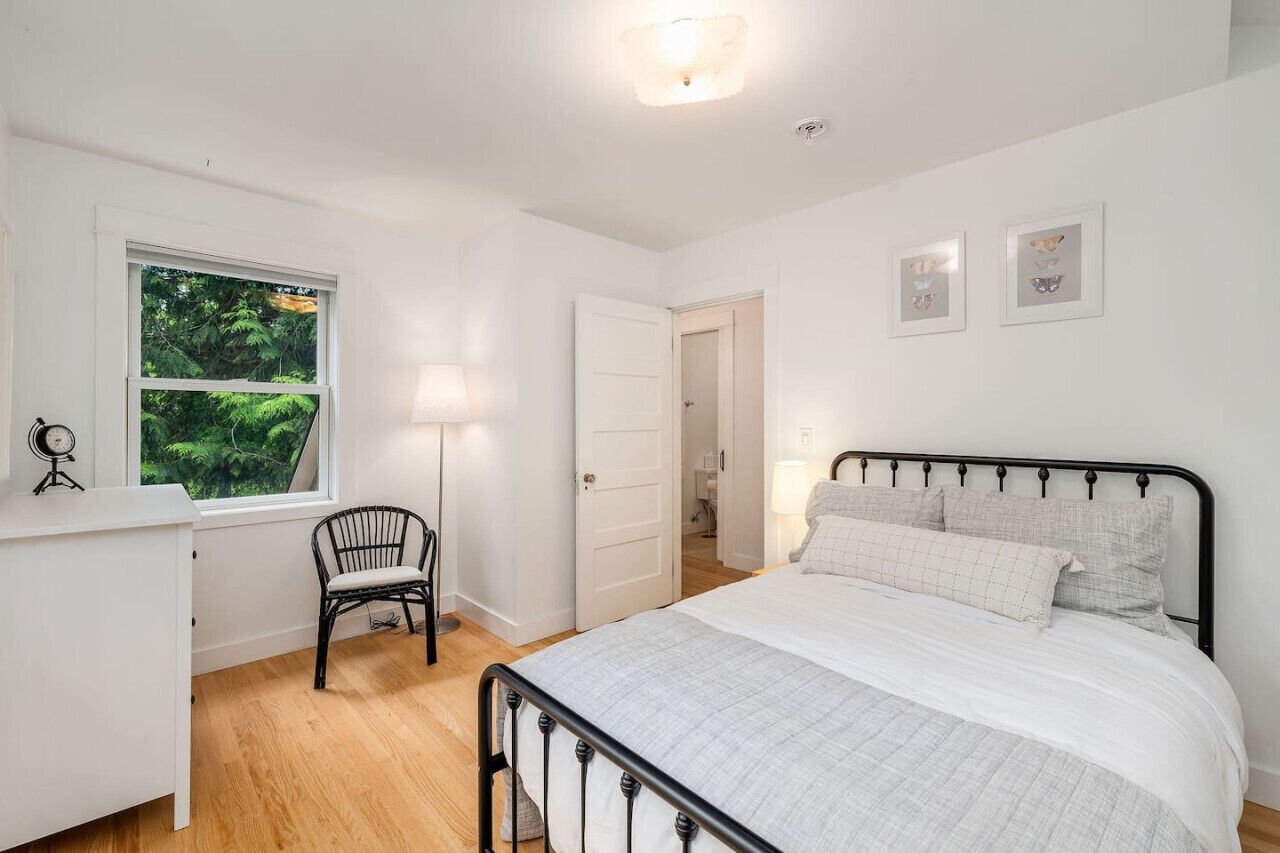 Une chambre à coucher comprenant un lit, une chaise, un bureau et une fenêtre donnant sur un paysage verdoyant.