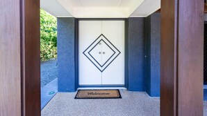 Een moderne entree met een geometrisch deurbontwerp en een welkomstmat.