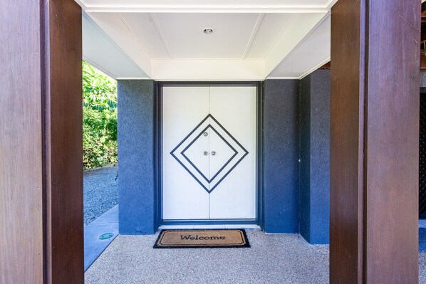 A modern entrance with a geometric door design and a welcome mat.