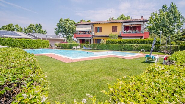 A residential property with a swimming pool, a well-maintained lawn, and a two-story house with a balcony. - Garda Orange Apartment - Italian Homing (Desenzano del Garda)