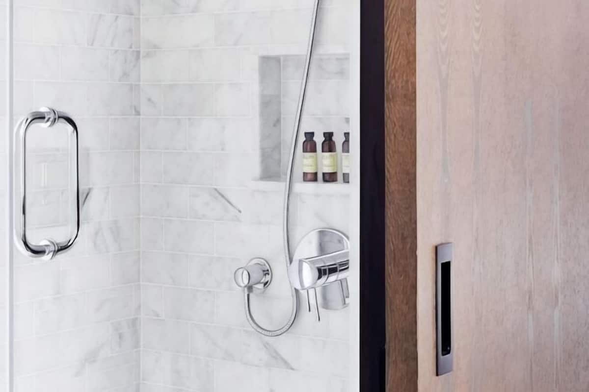 A bathroom with a shower, a toilet, and a shelf with toiletries.