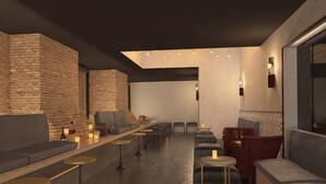 A modern lounge area with brick walls, seating, tables, and ambient lighting.