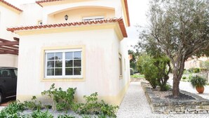 A single-story building with a tiled roof, a large window, and a small balcony. - Casa América - Praia Del Rey (Casal da Lagoa Seca)