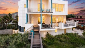A modern two-story house with a balcony, a staircase, and a pool.