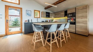A modern kitchen with wooden accents, a central island with bar stools, and built-in appliances.
